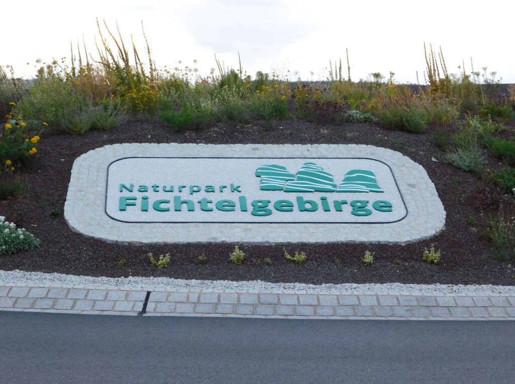 Logo Naturpark Fichtelgebirge, Grundgestell und Figuren aus Polymerbeton mit fest gebundenem farbigen Splitt und umlaufender Pflasterzeile