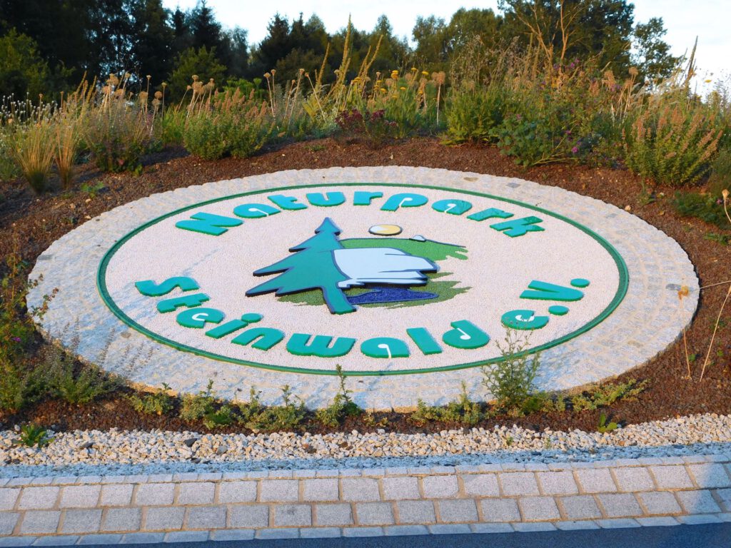 Logo Naturpark Steinwald, Grundgestell und Figuren aus Polymerbeton mit fest gebundenen farbigen Splitten und umlaufender Pflasterzeile
