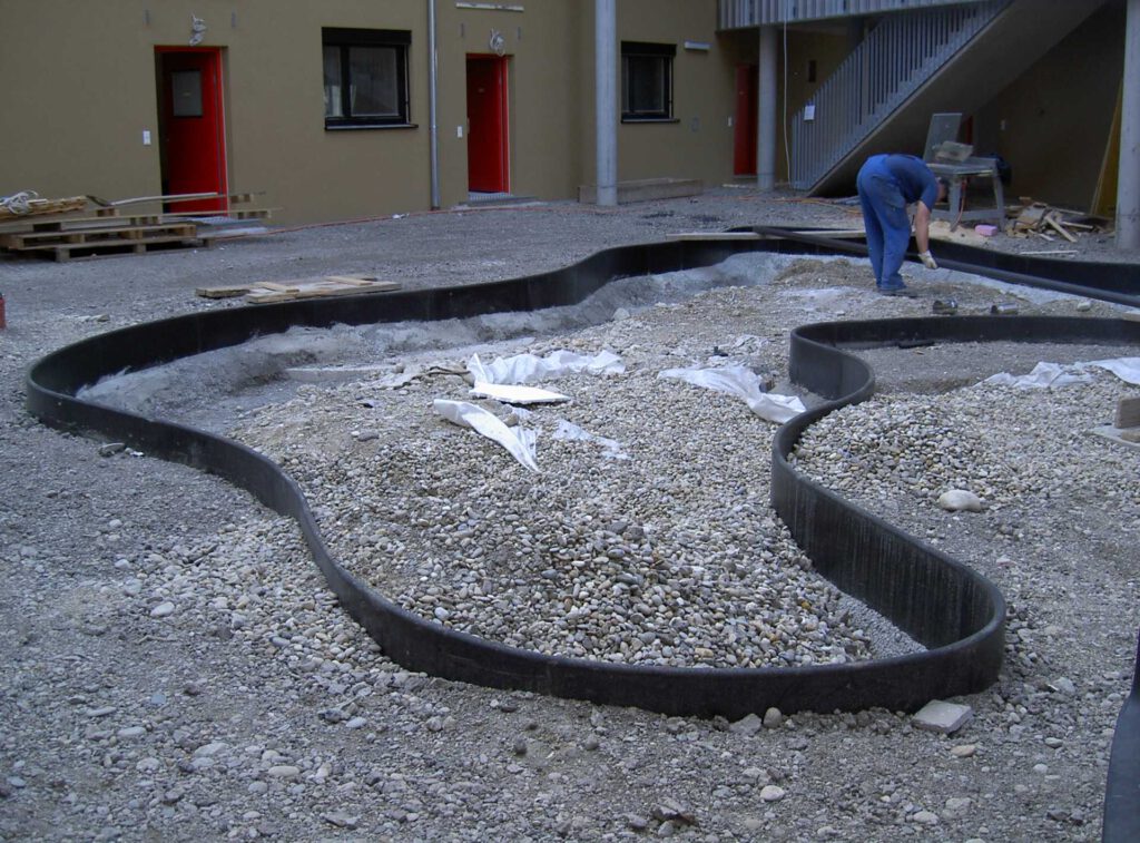 Sicherheitseinfassung aus Polymerbeton mit Fallschutzkante anthrazitfarben, Wasserspielplatz im Bau, Wien Seestadt Aspern