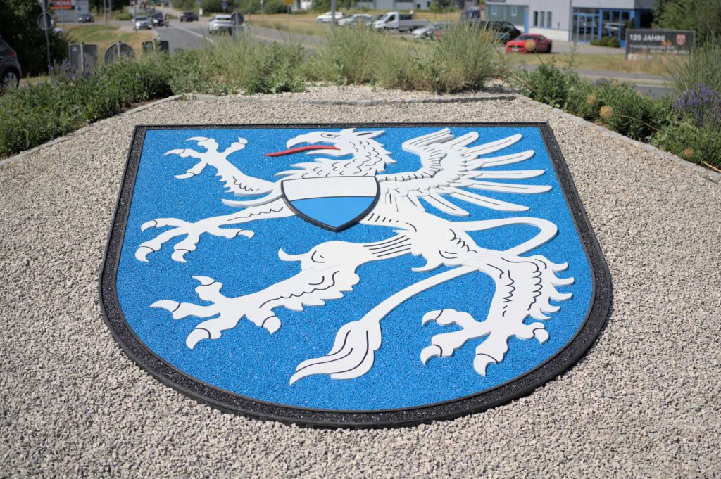 Wappen Freystadt im Kreisverkehr, Grundgestell und Figur aus Polymerbeton mit fest gebundenen farbigen Splitten, liegend in Schotter